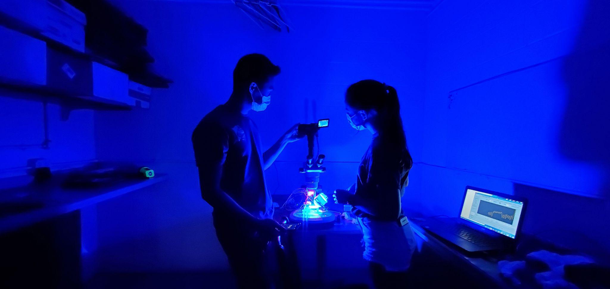 Students stand in a blue lit room with camera and science equipment.